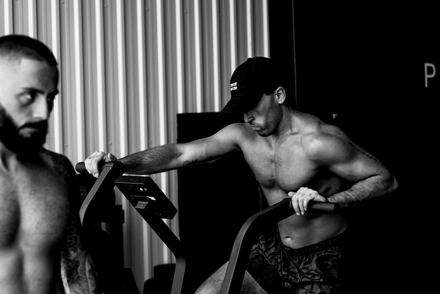 A man in a black cap working hard on an assault bike.