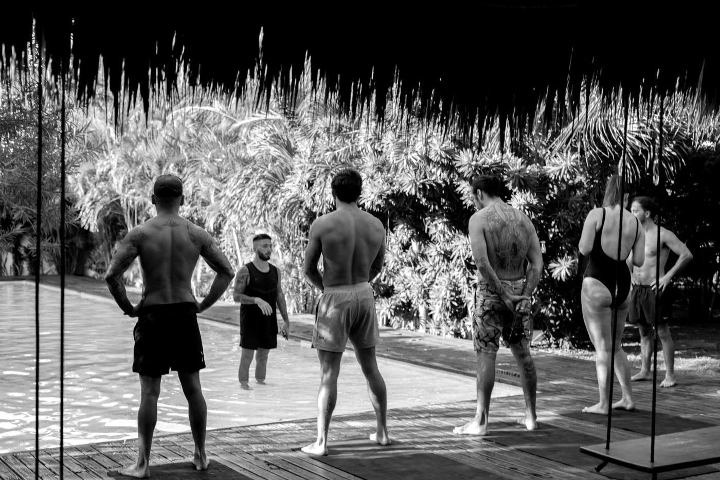 A group standing at the edge of a pool listening to a coach standing in the water.